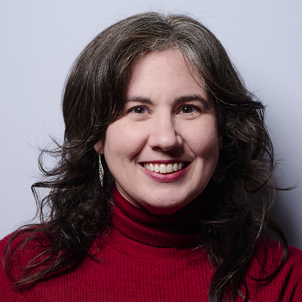 Katie Donnelly, a white woman with dark brown hair, a red turtleneck, and dangly earrings.